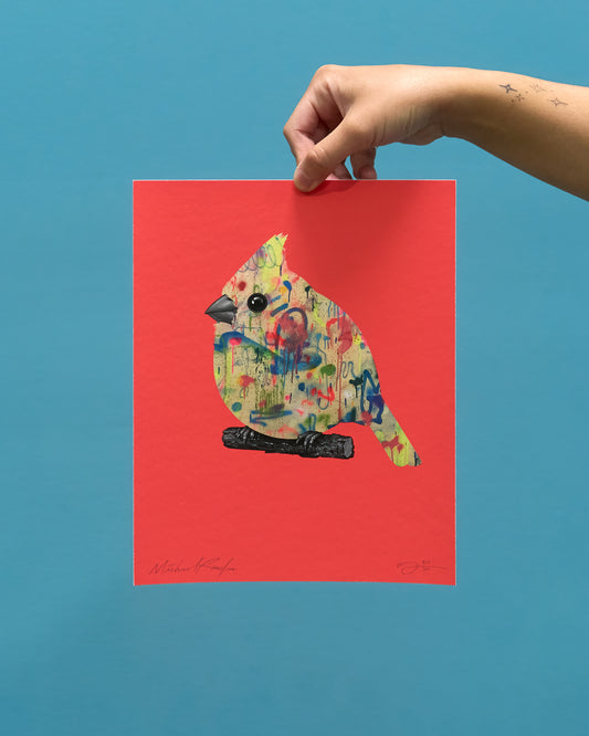 Colorful bird illustration print held by a hand against a blue background